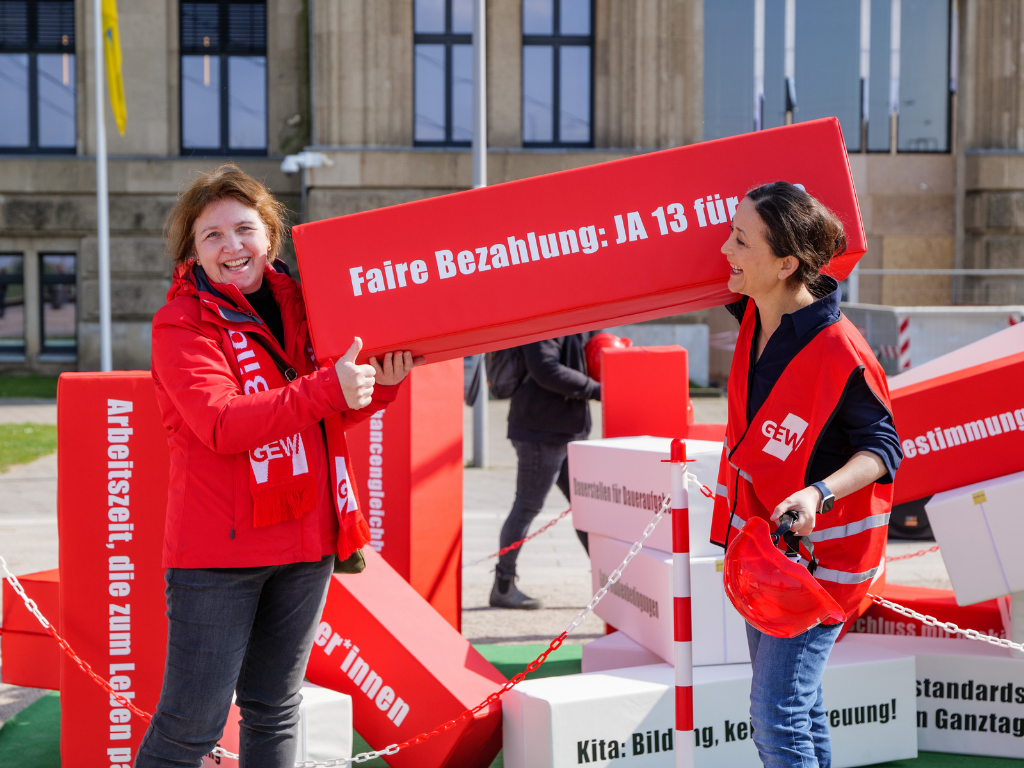 Ute Lorenz und Ayla Çelik tragen in der Baustelle Bildung den Baustein "Faire Bezahlung: JA 13 für alle!