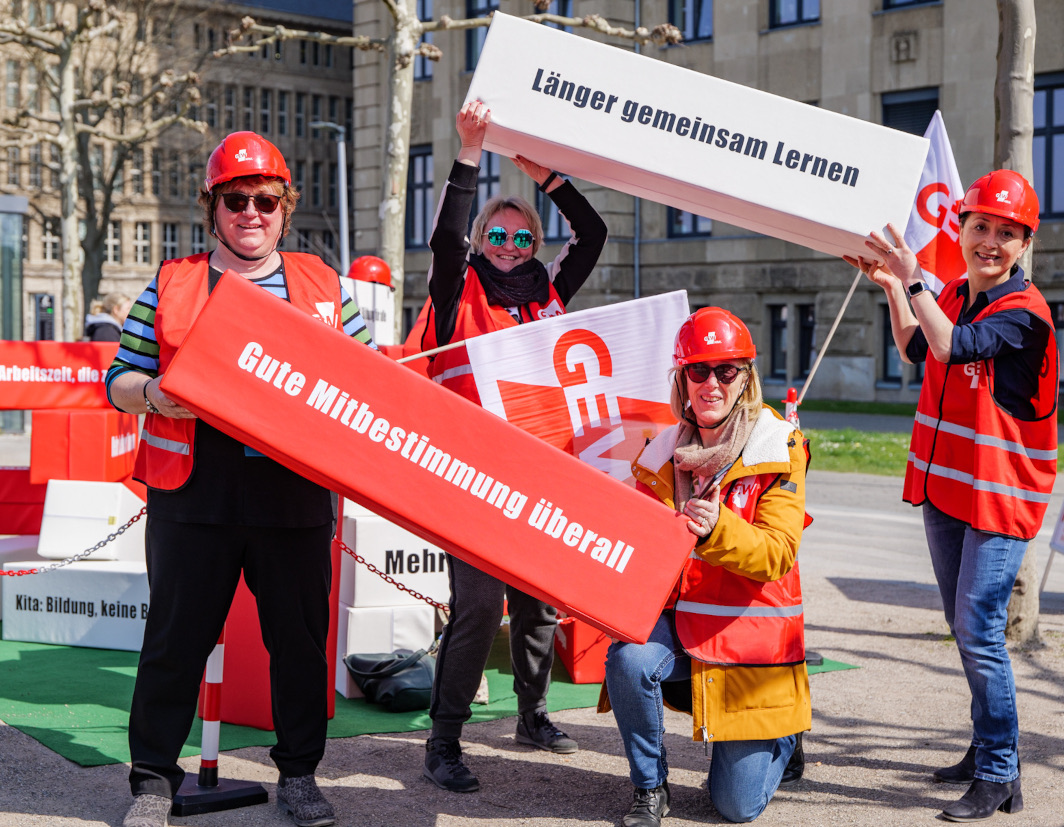 Aktive der GEW halten Bausteine mit Forderungen hoch.